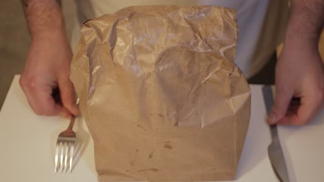 paquete de comida empacada en papel marrón con tenedor y cuchillo de mantequilla dispuestos