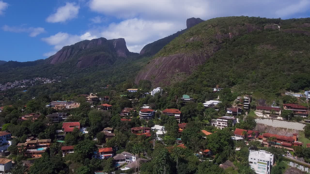 Vista aérea afastando-se de uma montanha, revelando casas na encosta no Rio