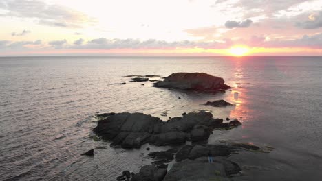 Toma-Aérea-De-Un-Dron-Sobre-Un-Joven-Disfrutando-Del-Amanecer-En-Las-Rocas-En-El-Mar-Cerca-De-Lozenets,-Bulgaria