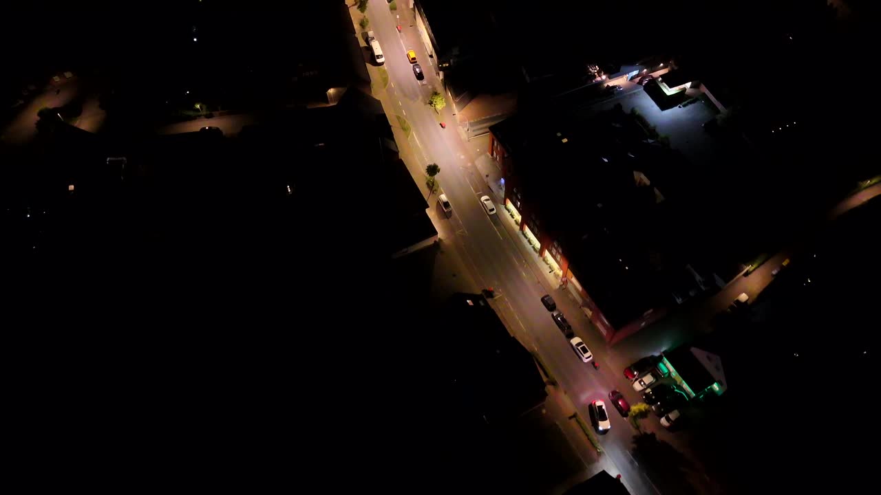Street with cars illuminated by lantern at night. Small American town in summer. Streetlights along main road of city. Aerial top down shot. Peaceful nightscape scene in United States