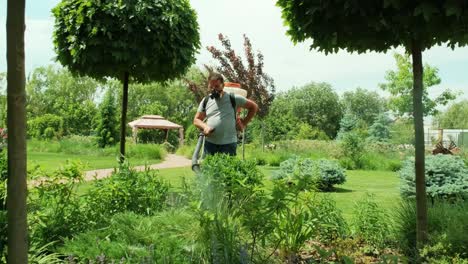 pulverizar pesticidas ecológicos. el agricultor fumiga en máscara protectora y gafas árboles y arbustos. el hombre rociando pesticidas tóxicos, pesticidas, insecticidas. el jardinero mantiene un jardín