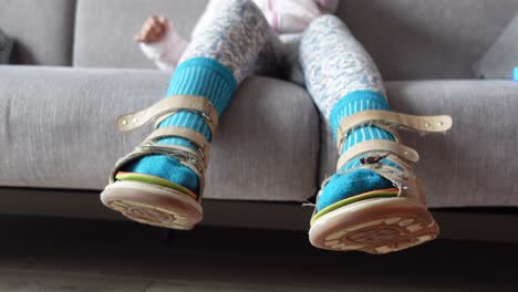 child with orthopedic sandals on a sofa