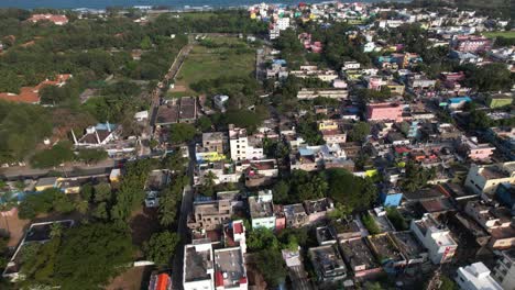aerial top view drone shot of buildings surrounded by trees near beach