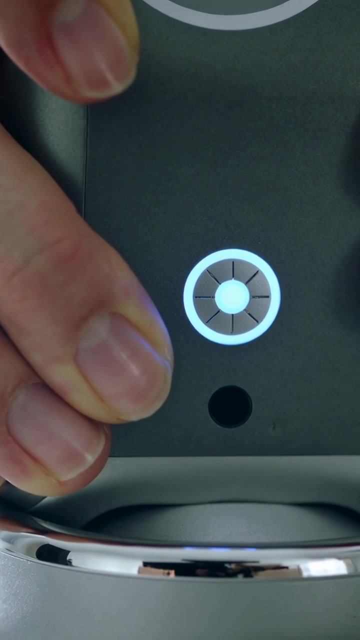 Vertical video: Pressing hand starting control on counter, lighting ring, disk near chrome spout