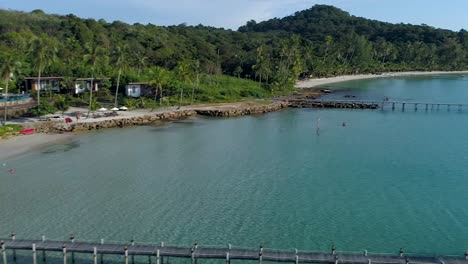 aerial, pan, drone shot of buildings on the coast and a paradise beach, on a sunny day, in koh kood, thailand