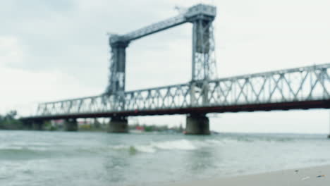 Aerial-view-river-bridge-sea-coastline-in-cloudy-weather.-Waves-crashing-beach.