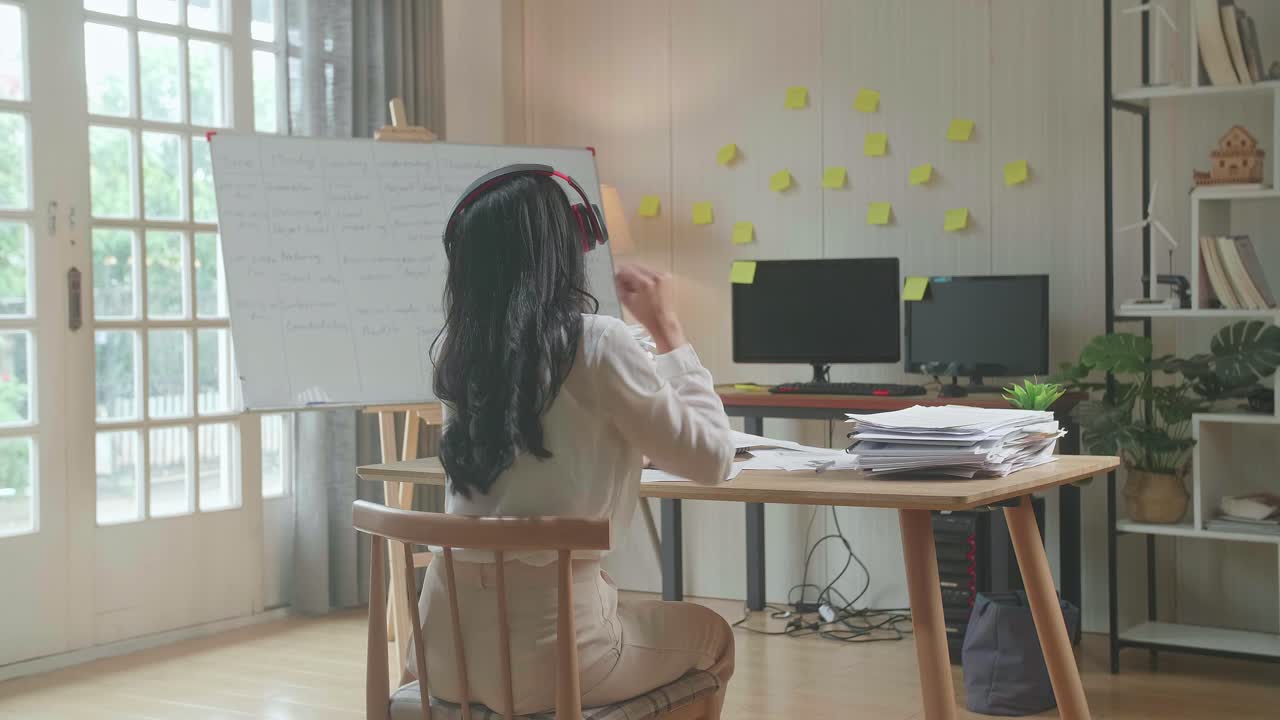 사무실에서 문서를 처리 한 후 춤추기 전에 음악을 듣기 위해 헤드폰을 착용 한 아시아 여성의 뒷면