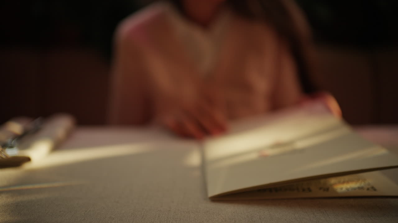 Close up of a person leafing through a menu in warm lighting at a restaurant