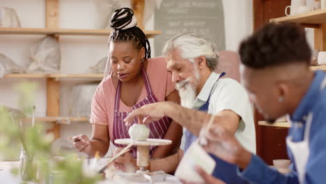 happy diverse group of potters glazing clay jugs and discussing in pottery studio