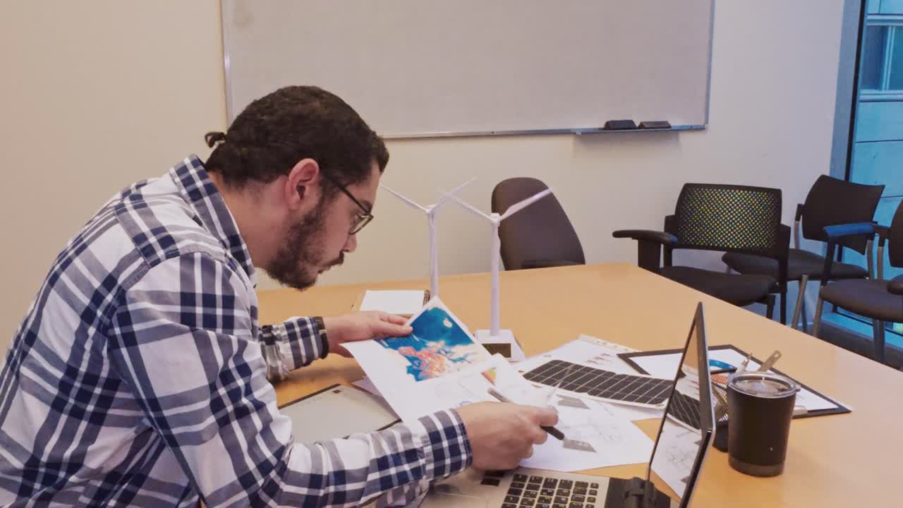 Male Designer Inspecting a Colorful Illustration for a Project