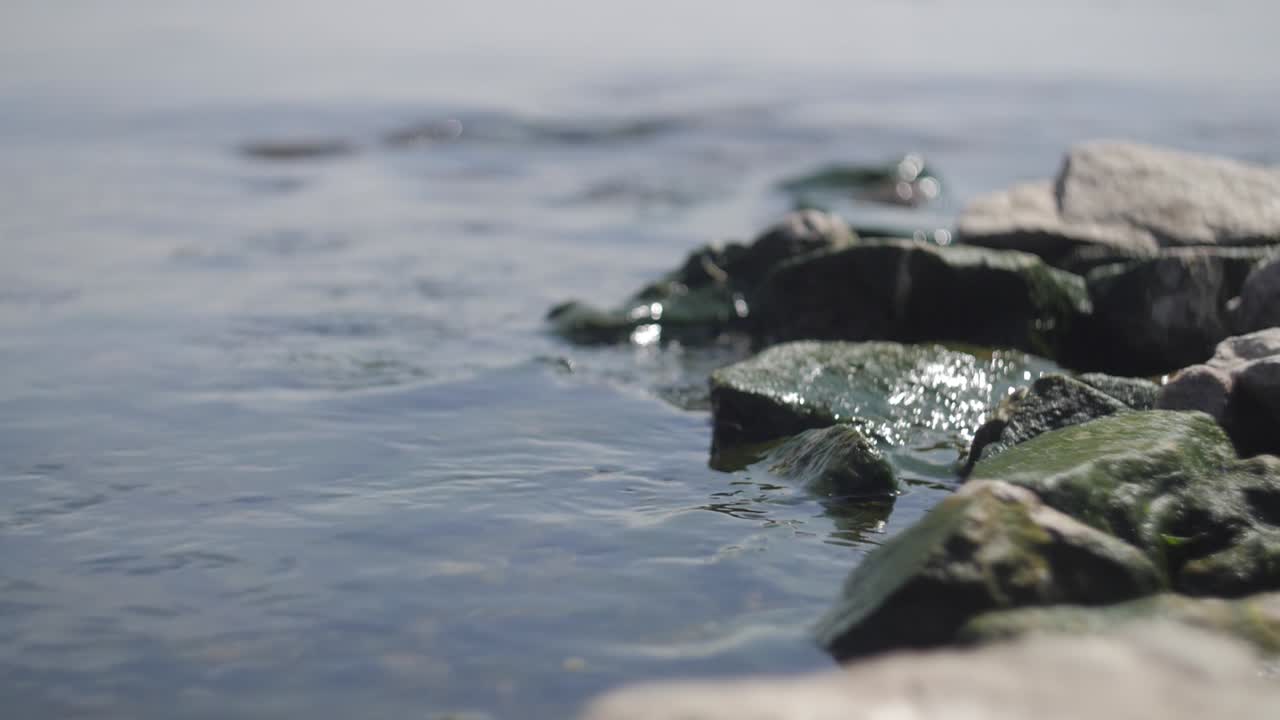 흐릿한 배경의 바닷물에 있는 바위와 아름다운 보케가 있는 느린 동작