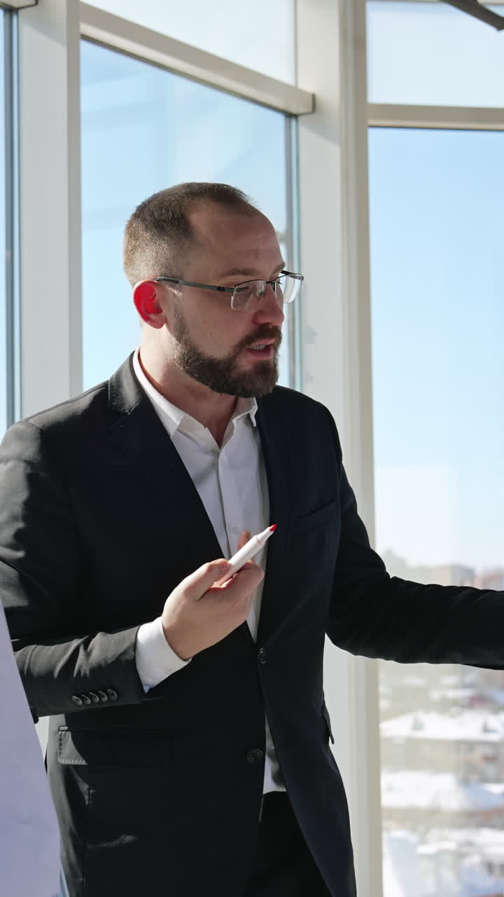 Speaker performs a speech in front of the colleagues. Businessman gives a speech and shows the curves at the chart. Vertical video