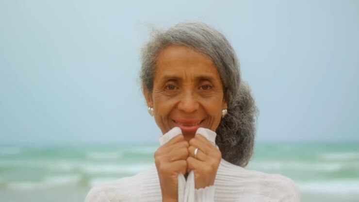 Front view of happy active senior African American woman standing on the beach 4k