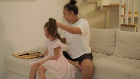 pregnant mother styling her daughter's hair at home