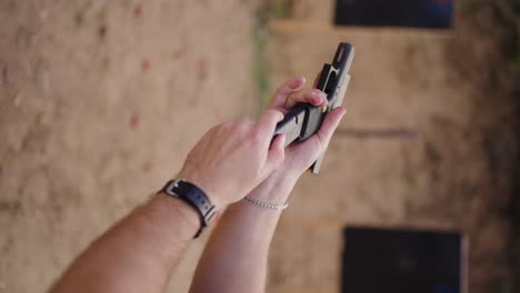 Vertical-shot-of-person-with-gun-change-magazine-with-combat-bullets-inside