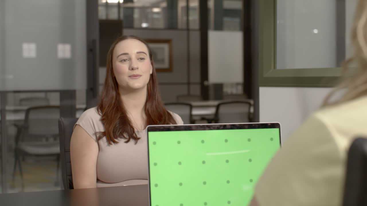 dos mujeres en sus 20 años en un entorno de oficina hablando entre sí con un video dolly disparado moviéndose de izquierda a derecha