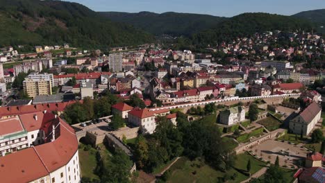 drone semi orbit capturing the full structure of decin castle and town, with river and hills under blue sky