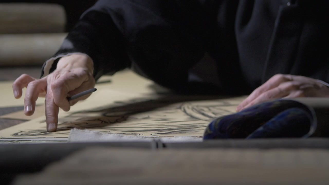 Primo piano di un artista che sfuma il carboncino su un grande disegno su carta usando un dito mentre tiene un carboncino. Concetto di tecnica artistica, sfumatura, perfezionamento dello schizzo, creatività e arte visiva