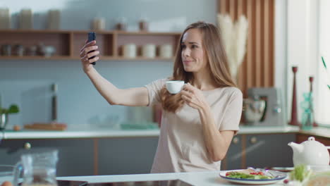 mujer tomando selfies en el teléfono inteligente en la cocina