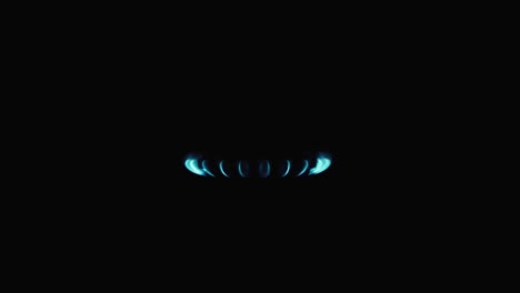 burning gas stove hob, blue flames macro close-up in the dark on a black background. gas is switching on, apearing blue flame. gas stove on isolated on a black background.