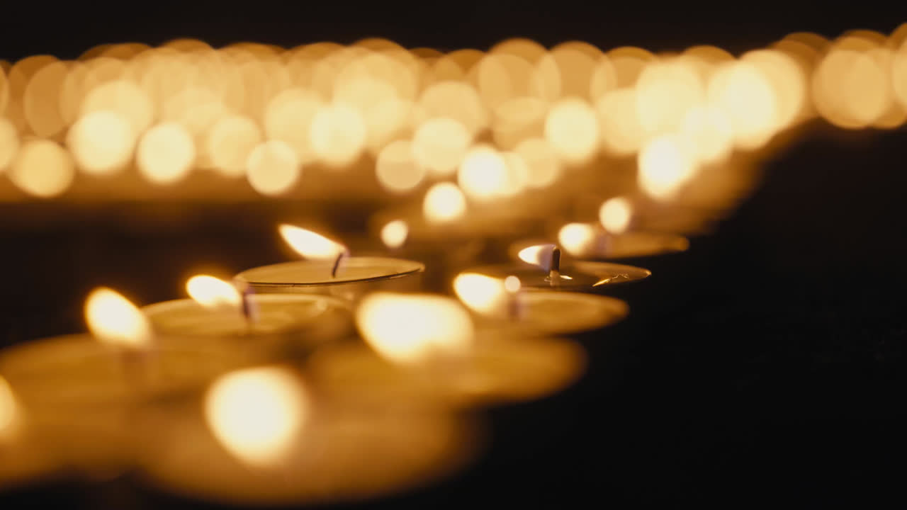 เทียนทีไลต์หลายดวงส่องแสงในความมืดพร้อมพื้นหลังโบเก้นุ่มนวลในช่วง Earth Hour ซึ่งเป็นสัญลักษณ์ของการมีส่วนร่วมของชุมชนในการดำเนินการด้านสภาพอากาศโลก