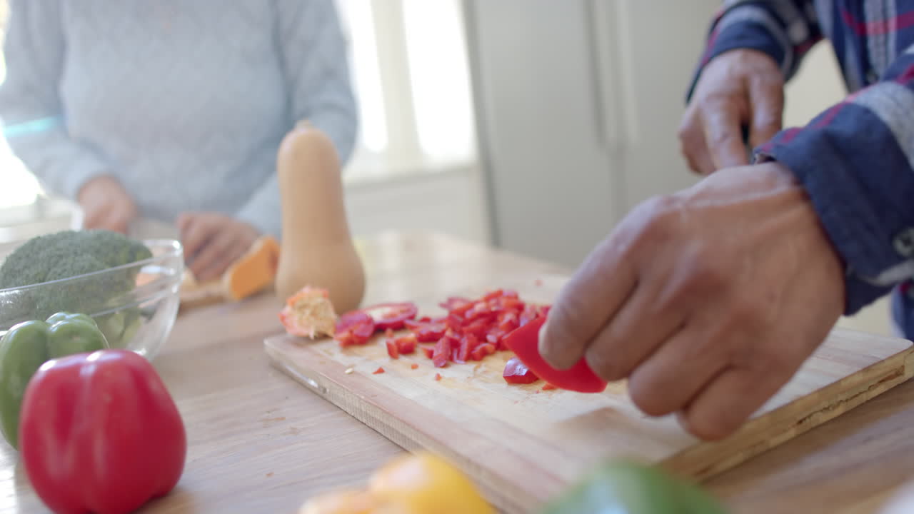 se centró en la cocina de una pareja diversa, cortando verduras en la cocina, en cámara lenta.