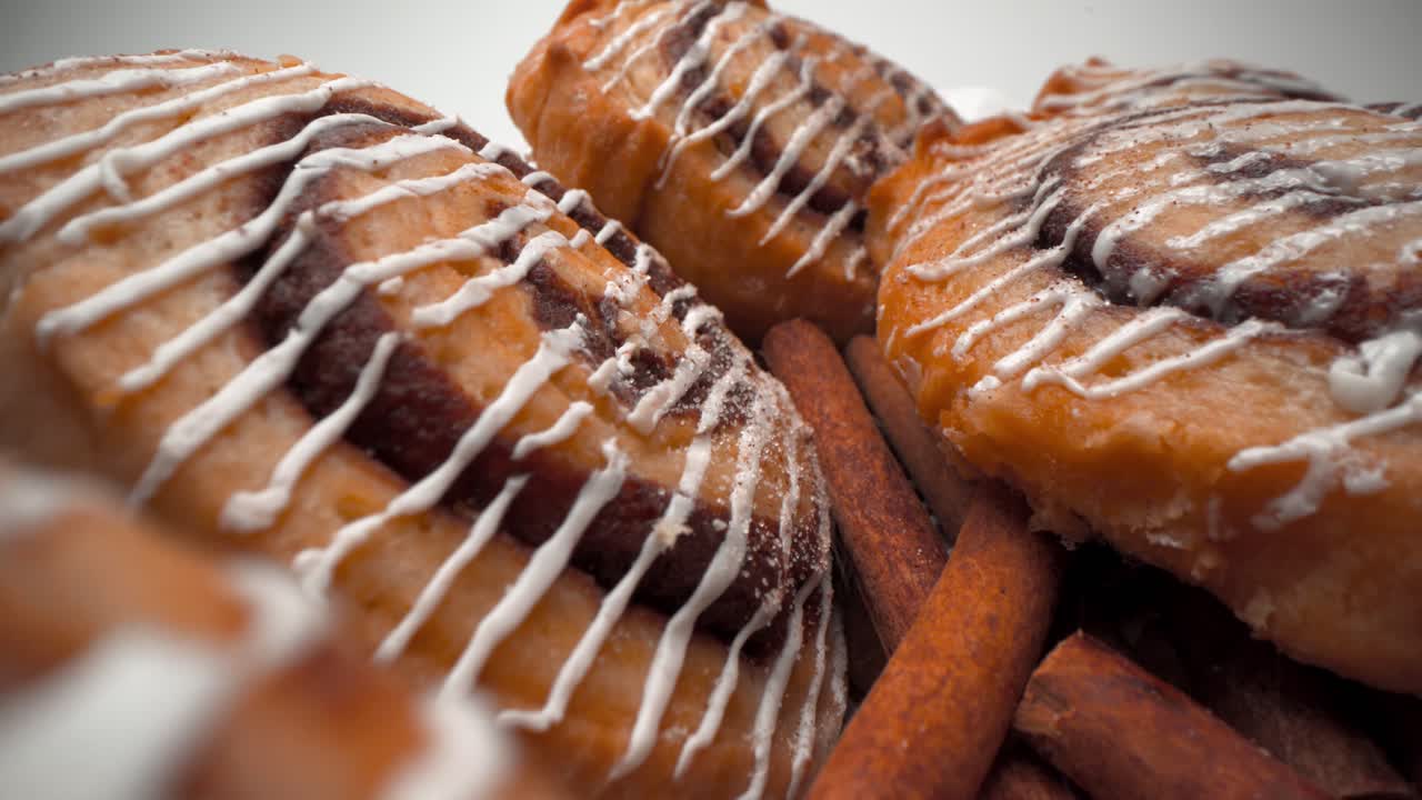 башня из булочек с корицей и аппетитной глазурью макрос крупным планом с палочками корицы и посыпанием пылью отъезжающий зонд 4k видео продукта