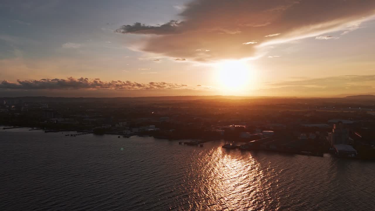 Cinematic drone footage of a city coastline in the Philippines at sunset with golden reflections on the ocean, ideal for travel, lifestyle, and cinematic projects