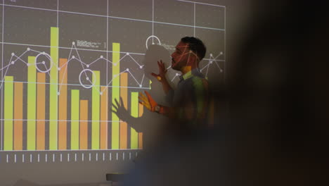 maestro masculino dando una lección de matemáticas o ciencias en la escuela de pie en la parte delantera de la clase con la proyección del gráfico 4