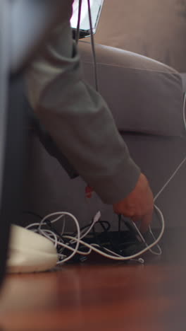 vertical video close up of person at home untangling electric power leads and connection cables for laptop or other electronic device