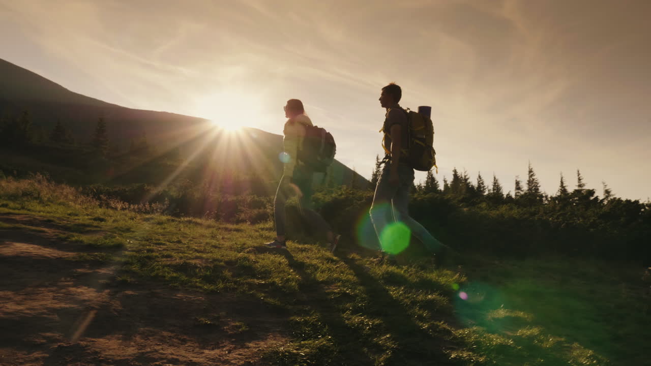 dos escaladores suben la montaña en el concepto de vista lateral del sol - victorias y logros steadicam sh