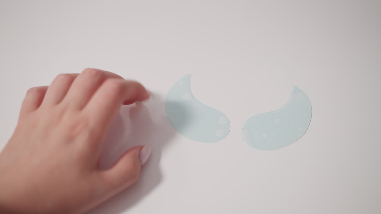 con la manicura clásica femenina coloca parches hidratantes para los ojos en una superficie lisa. los parches para los ojos dispuestos en forma de alas se encuentran en la mesa listos para su uso