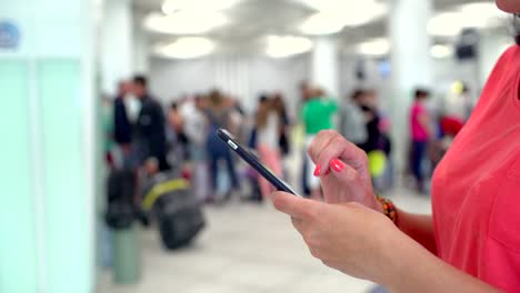 traveler woman, close-up of female hands texting messenger or typing sms on smart phone in terminal of airport