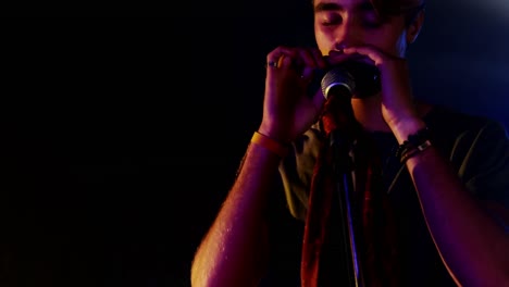 hombre tocando la armónica en un club nocturno 4k