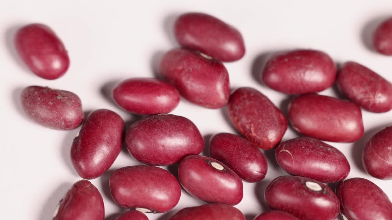 Close-up of red bean seeds scattered on a white background, showcasing texture and color in a macro perspective