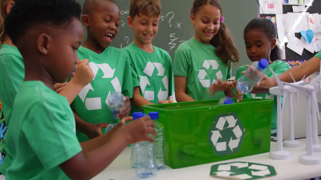 Mixed-race schoolkids putting recycle bottles in the tray at classroom 4k