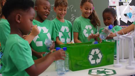 Mixed-race-schoolkids-putting-recycle-bottles-in-the-tray-at-classroom-4k