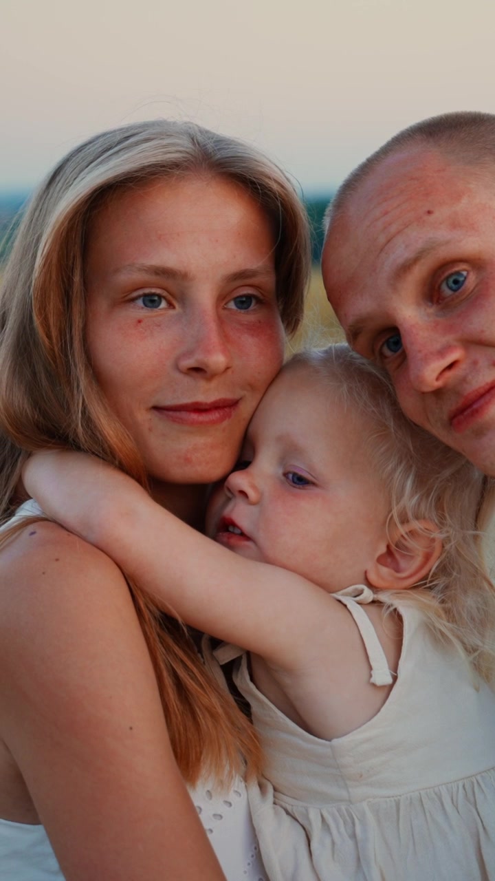 Ung familie omfavner hinanden udendørs ved solnedgang