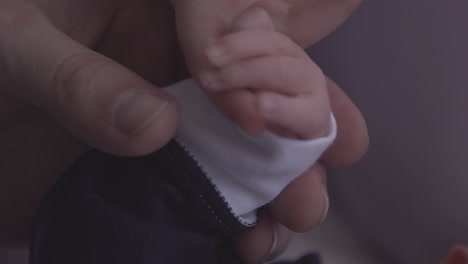 baby holds sister finger and dad stroking children closeup