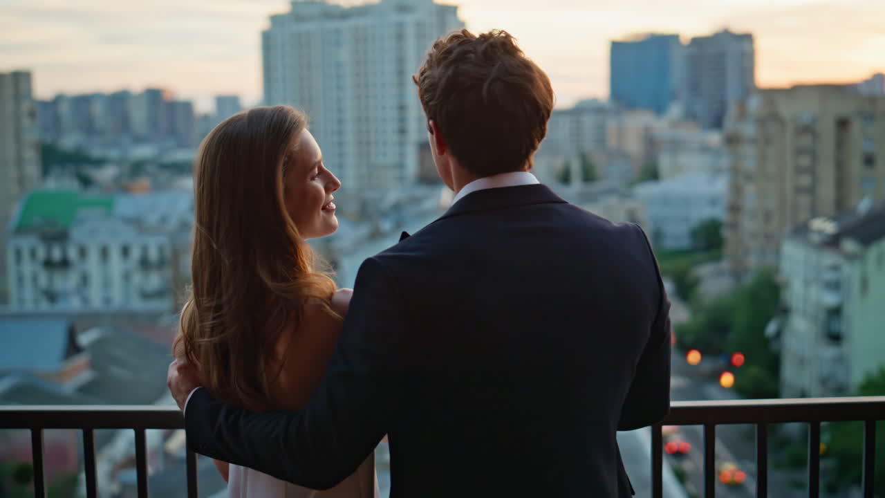 Romantic couple embracing balcony watching city twilight closeup back view