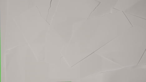 stop motion sequence of torn pieces of paper moving to uncover green screen background below