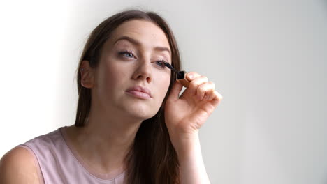 studio shot of attractive woman putting on mascara