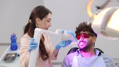a patient receives professional oral health care from a dental team. during a routine visit, the dentist and assistant work on a tooth, illustrating a standard procedure for maintaining healthy teeth.