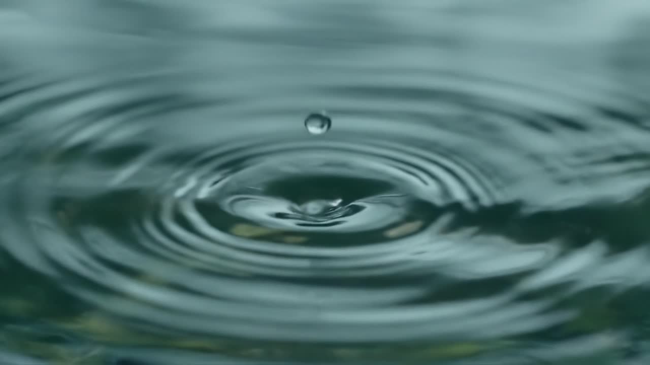 Captivating Close-Up of a Water Drop Creating Ripples on a Calm Surface, Showcasing the Intricacies and Beauty of Nature's Fluid Dynamics in Slow Motion