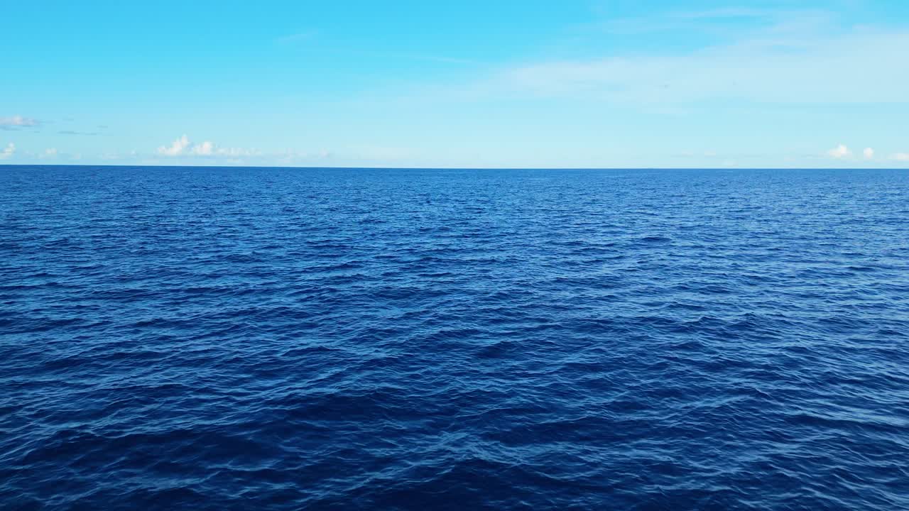 Slow aerial over calm, expansive blue ocean with soft ripples, perfect for serene and peaceful backdrops