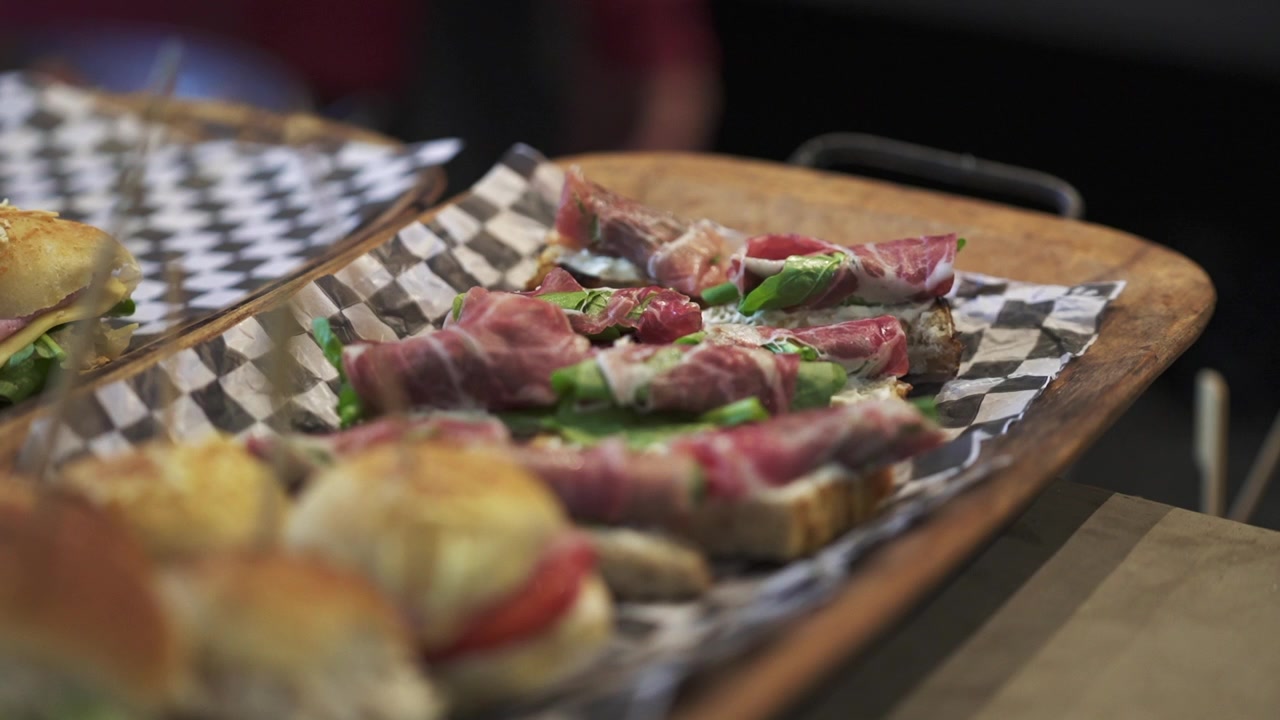 Vista ravvicinata di alcuni antipasti con prosciutto e lattuga su un tagliere rustico.