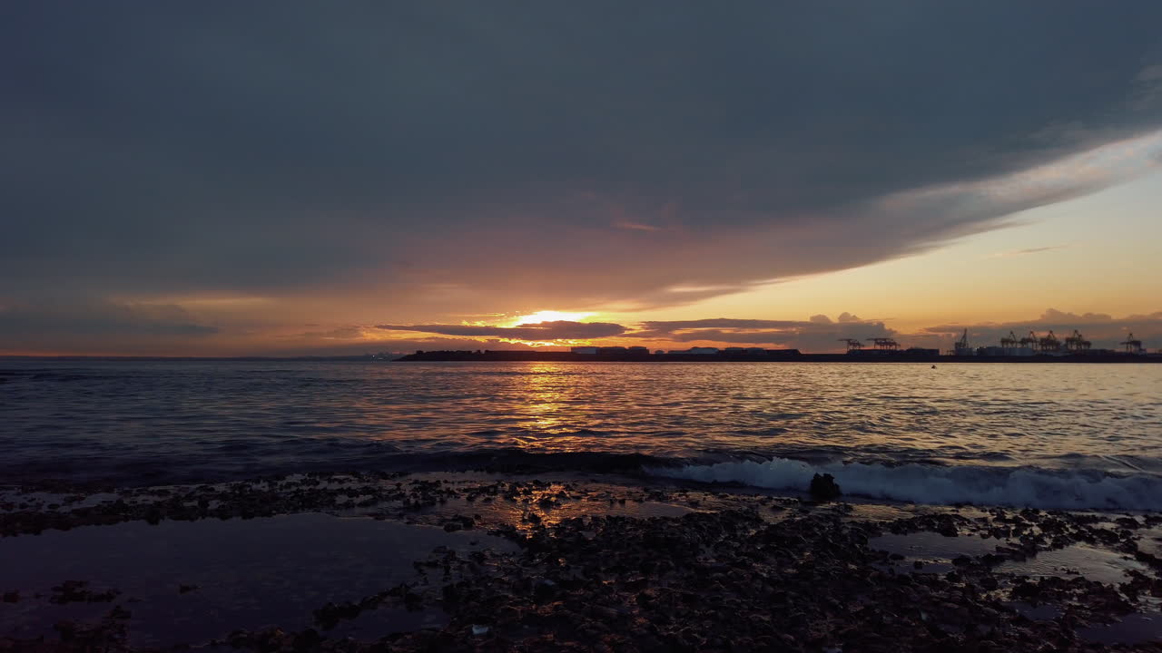 Orange sunset on shore of Australia with dramatic large grey cloud