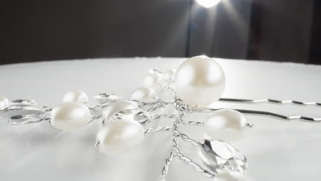 shimmering white pearl necklace with crystal accents reflecting light on a white table