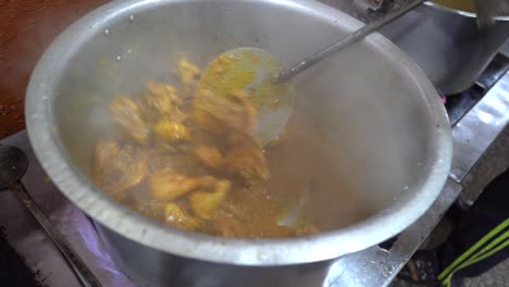 professional chef stirring and cooking spicy mughlai chicken curry stew in a hotel kitchen