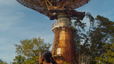 Amazing-view-as-young-girl-smells-the-roses-before-looking-up-at-a-massive-radar-tower-tracking-sation